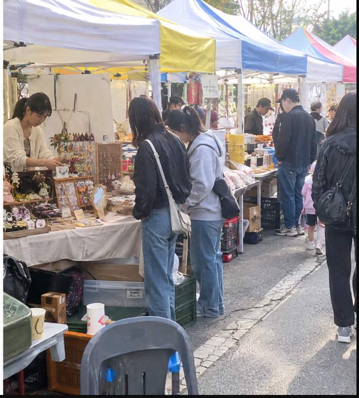 Dada Hand Market craft stalls with visitors browsing handmade goods along Jangwi New Town streets at Dada Festa
